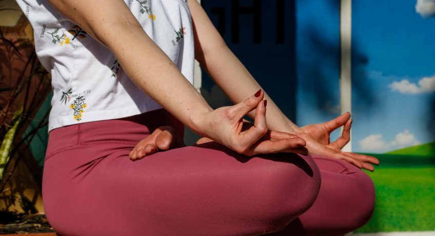 Close up shot of legs in lotus and hands resting on knees in gyana mudra.